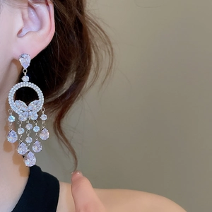 Vue détaillée des boucles d'oreilles papillon argentées avec pompons en zircone étincelants