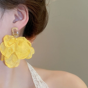 Detail of bright yellow organza flower earring featuring a clear resin square stud