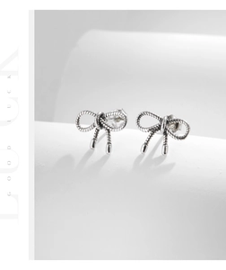 Detailed close-up of S925 silver bow stud earrings featuring vintage rope textures