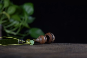 Close-up of a carved sandalwood gourd diffuser pendant showing the unscrewed internal part