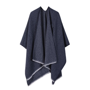 Close-up of the dark blue woven fabric texture and tassel fringe hem of the poncho shawl