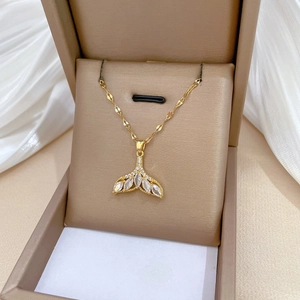 Elegant gold fishtail necklace with sparkling cubic zirconia displayed in a beige jewelry box