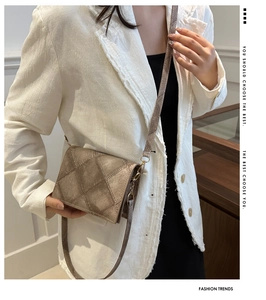 Dettaglio borsa a tracolla trapuntata marrone con hardware dorato su blazer in tweed