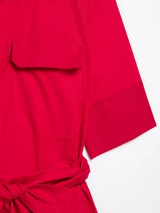 Detail of red poplin dress featuring side pockets and elegant waist bow tie detail