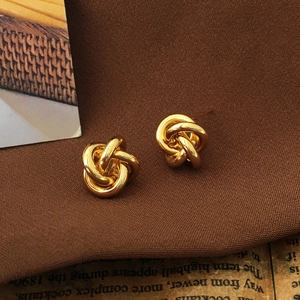 Detailed close-up of golden knot earrings on vintage background with elegant fabric texture
