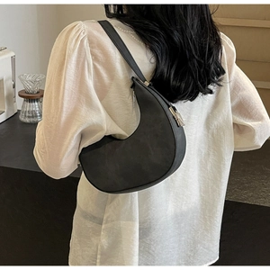 Detail of minimalist black crescent underarm bag with silver zipper and matte finish