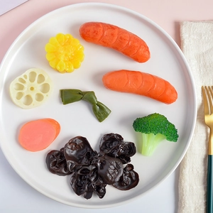 Detailed view of realistic PVC artificial vegetable set with corn and sausage on a plate