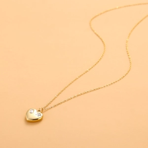 Detail of gold heart pendant necklace featuring micro-set cubic zirconia and link chain