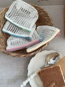 Transparent mesh coin purse with colorful zippers and metal ring in a woven basket