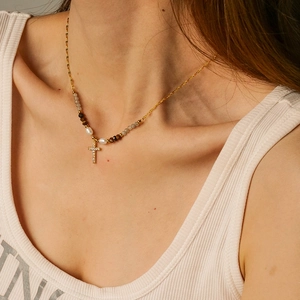 Gold-plated cross necklace with white pearls and assorted natural stones on female model