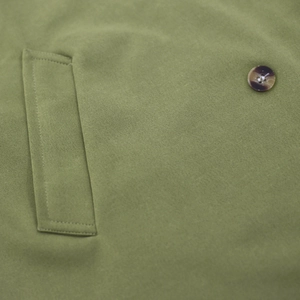 Detailed close-up of olive green coat pocket featuring a marble-textured brown button