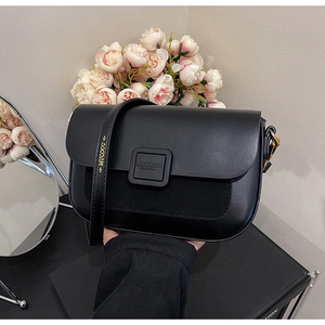 Detail of black patchwork shoulder bag with smooth leather and suede flap on a floral setting