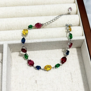 Detailed close-up of a silver chain bracelet with oval-cut rainbow crystals in a jewelry box