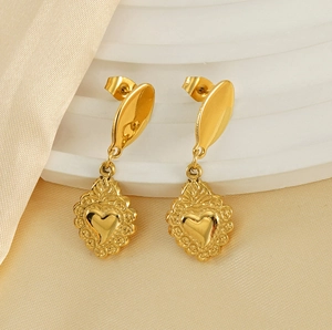 Detail of gold heart earrings with vintage embossed patterns on champagne silk