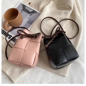 Detailed shot of pink and black woven phone bags with knotted straps on beige texture