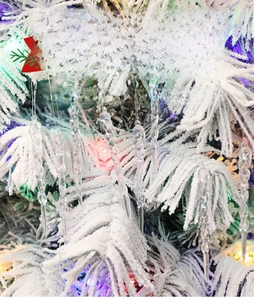 Macro view of transparent spiral icicle ornaments hanging on a frosted Christmas tree