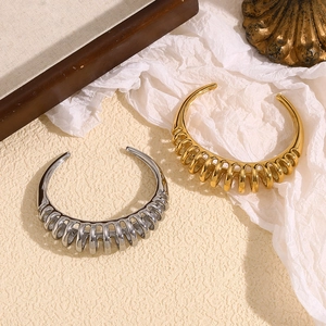Detailed close-up of C-shaped spiral wave bangles in polished gold and silver finishes