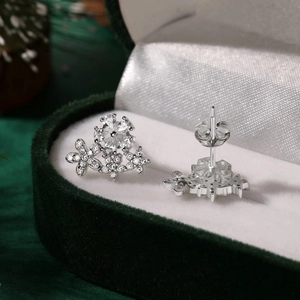 Macro view of crystal flower earrings with sparkling zircons on green velvet