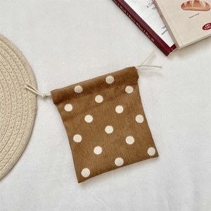 Close-up of brown corduroy drawstring bag with white polka dots and texture detail