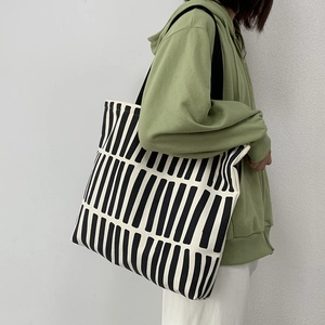 Close-up of minimalist black and white striped canvas tote bag worn by a model