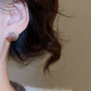 Gros plan de boucles d'oreilles en résine rose translucide portées par un mannequin