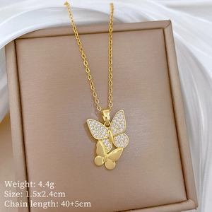 Detail of gold double butterfly necklace with crystals on beige jewelry box