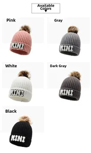Detail view of multi-color beanie hats with faux fur pom poms and MINI letter embroidery