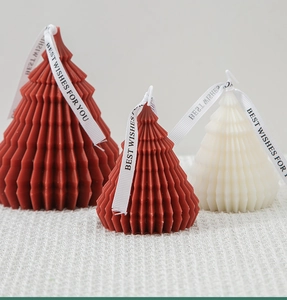 Detailed view of white and red origami Christmas tree candles with ribbing and ribbons