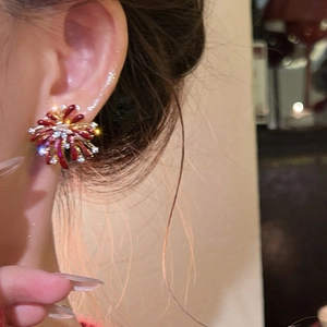 Close-up of red flower-shaped earrings with gold accents and sparkling cubic zirconia