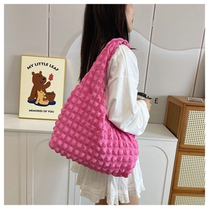 Pink ruched bubble tote bag being worn as a shoulder bag in a natural home setting