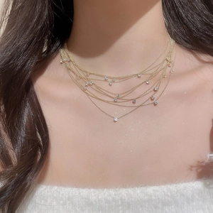 Detail of multi-layer gold chain necklace with zircon pendants on model neck