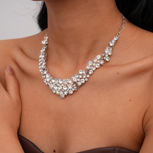 Détail d'un collier argenté en V avec strass porté par un modèle pour soirée chic