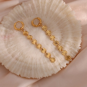 Close-up of 18K gold plated snowflake chain earrings on white coral texture background