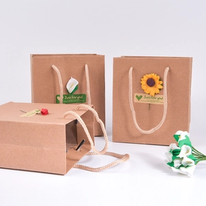 Vintage kraft paper gift bags with decorative flowers and rope handles on white background