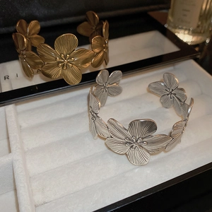 Macro detail of vintage floral open cuff bracelets in antique gold and silver finishes