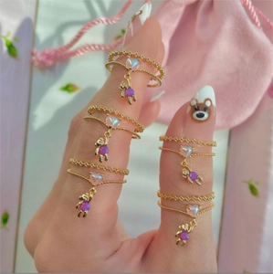 Detail showing five golden chain rings with cute purple bear and heart charms on hand