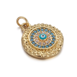 Macro detail of golden Evil Eye round pendant with blue crystal inlay and textured gold border