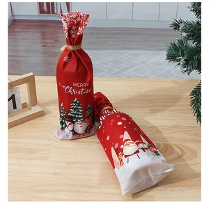 Detail of red Christmas wine bottle bags with Santa Claus print on a wooden table