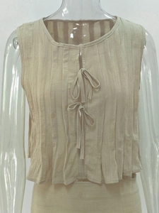 Detail of beige pleated sleeveless top featuring front dual bow tie closures and texture