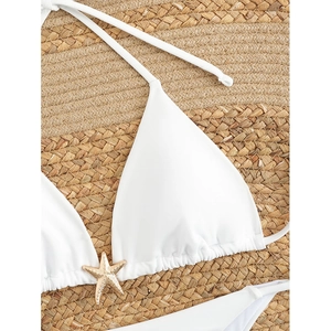 White halter bikini top featuring a central gold starfish detail on beach mat background