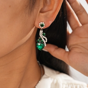 Gros plan de boucles d'oreilles en argent avec pierres vertes en cœur et zircons brillants