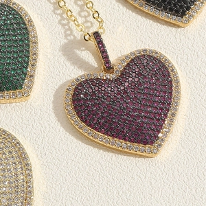 Macro detail of heart-shaped pendants featuring colorful micro-pave zircons and gold plating