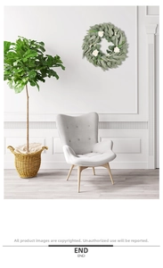 Artificial eucalyptus and white rose wreath displayed on a white wall in a modern room