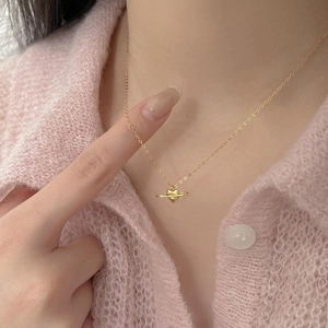 Detailed view of a golden heart planet pendant necklace worn on a pink knit sweater