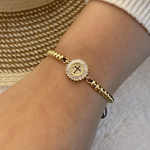 18K gold beaded bracelet with zircon cross charm on black braided cord worn on wrist