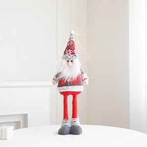 Standing Santa gnome plush with red snowflake hat and warm holiday light background