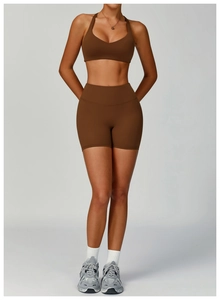 Detail of high-waist chocolate yoga shorts and halter sports bra in matte finish