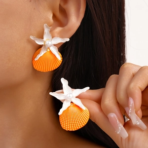 Detail showing orange scallop shell earrings with pearl and starfish on model