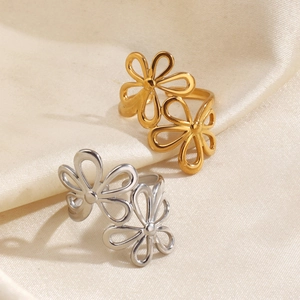 Adjustable hollow flower rings in gold and silver finish on elegant beige silk fabric
