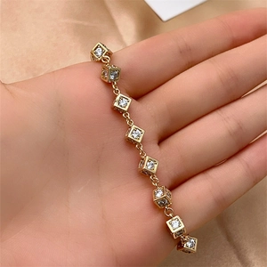 Elegant gold bracelet with minimalist cube pendants and sparkling zircon stones on silk